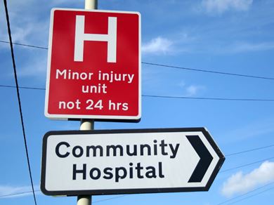 Community Hospital and Minor Injury Unit road signs with a blue sky background