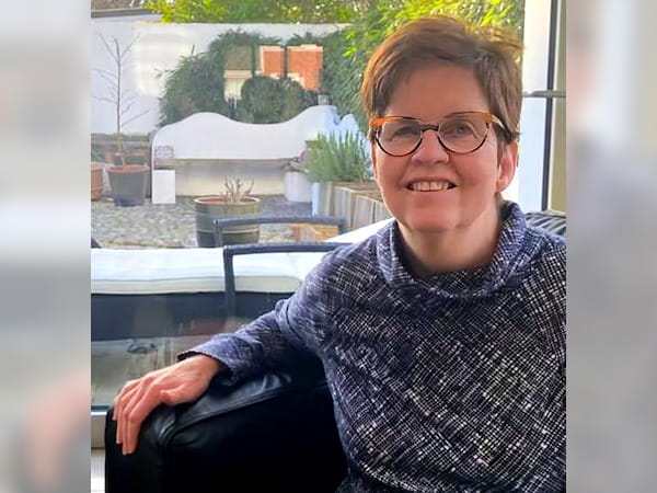 Kathleen O’Leary is sitting in a chair in front of a window.