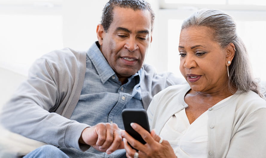 An older man and woman are looking at a smartphone.