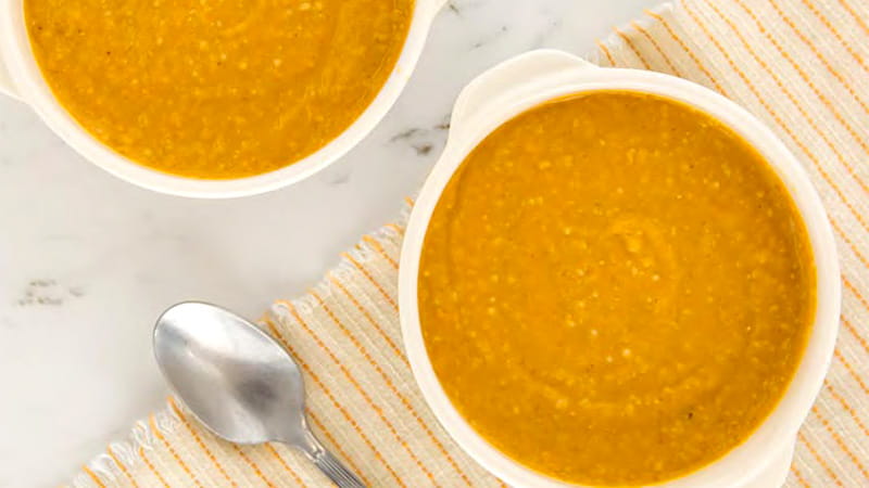an aerial view of two bowls of pumpkin oatmeal and a spoon on a table