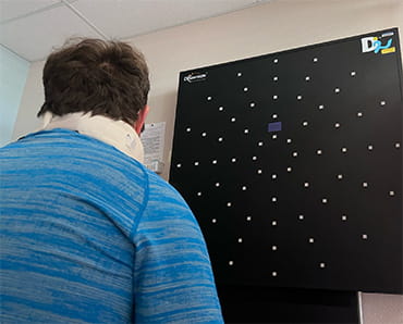 Stroke survivor, Rory Polera, is looking up at a device on the wall as part of his therapy.