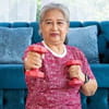 A senior Asian woman is sitting on her living room floor lifting dumbbells to her chest.