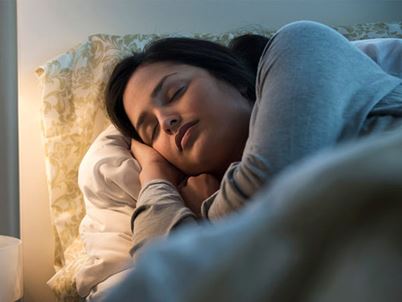 A Hispanic/Latina woman is sleeping in bed.