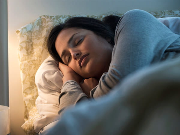 Una mujer de origen hispano/latino duerme en una cama.