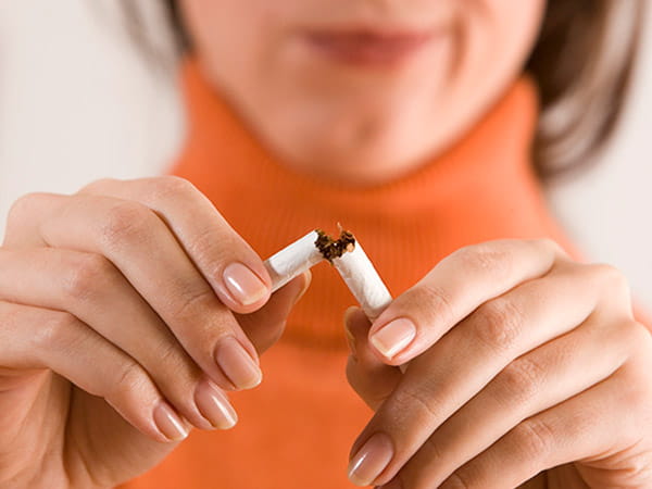Primer plano de una mujer rompiendo un cigarrillo.