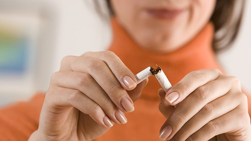 Primer plano de una mujer rompiendo un cigarrillo.