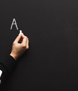 Woman writing the letter A on a chalkboard